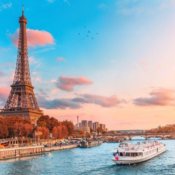 The main attraction of Paris and all of Europe is the Eiffel tower in the rays of the setting sun on the bank of Seine river with cruise tourist ships (The main attraction of Paris and all of Europe is the Eiffel tower in the rays of the setting sun o