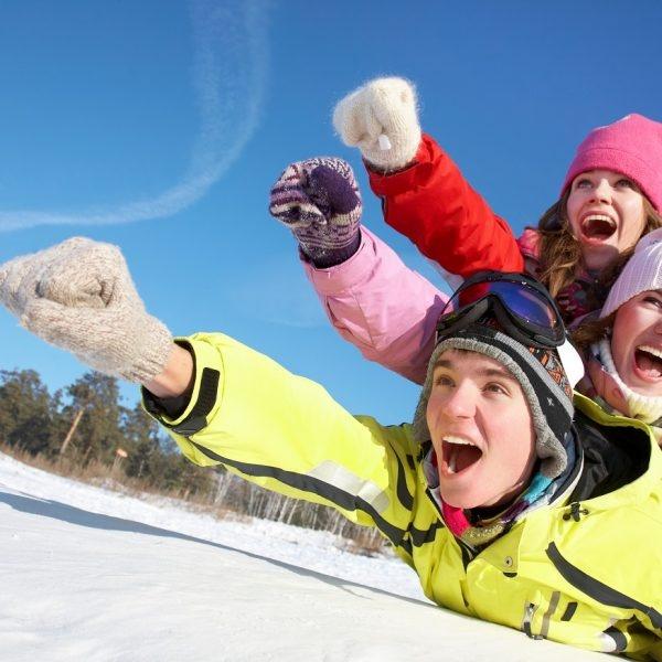 Group of  teenagers slide downhill in wintertime